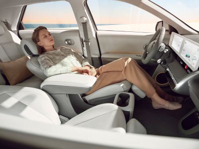 En dame slapper av i førersetet på IONIQ 5 med setet langt tilbake. Foto.