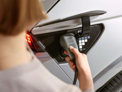 Une personne branchant le câble de charge sur la prise latérale de IONIQ 5, le crossover compact 100 % électrique de Hyundai.