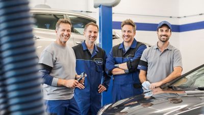 Hyundai service team stood together being vehicle.