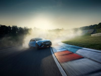 The all-electric Hyundai IONIQ 5 N drifting sideways through the curve of a racetrack seen from front.