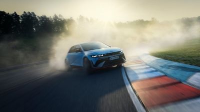 The all-electric Hyundai IONIQ 5 N drifting through a curve on a racetrack with smoking tyres.