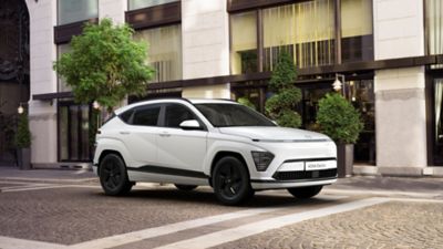 Hyundai KONA Electric Pure Edition driekwart van voren in straat met gebouw op achtergrond.
