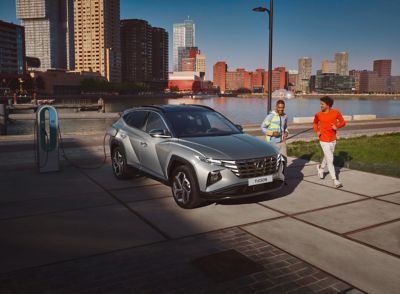 The all-new Hyundai TUCSON Plug-in Hybrid compact SUV parked in front of a house with a family. 