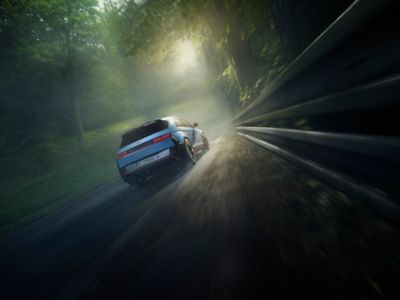 A Hyundai IONIQ 5 N high-performance EV seen from behind driving on a racetrack with trees.