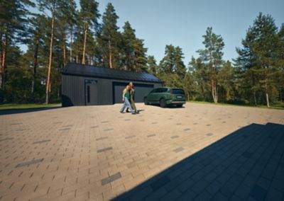 Hyundai IONIQ 9 è parcheggiata davanti a un garage, con due persone che camminano accanto.