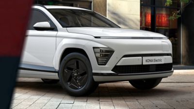Detailfoto voorzijde Hyundai KONA Electric Pure Edition in straat met gebouw op achtergrond.