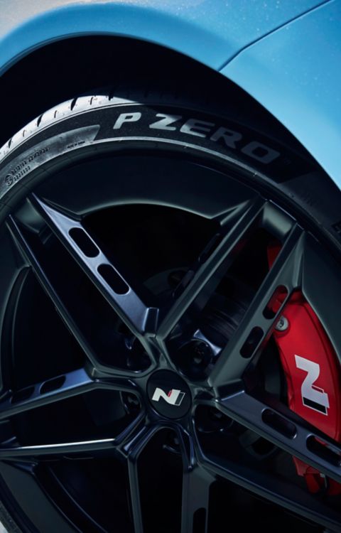 Wheel detail with black alloy rim featuring angular aero-inspired design.
