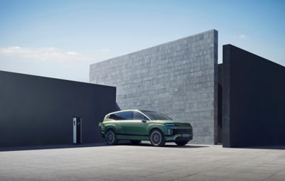 SUV elettrico Hyundai IONIQ 9 collegato alla ricarica davanti a una casa.