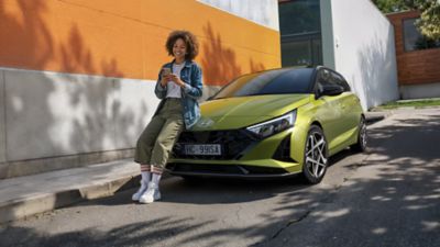 Ragazza cammina di fronte al retro di Hyundai i10 azzurra