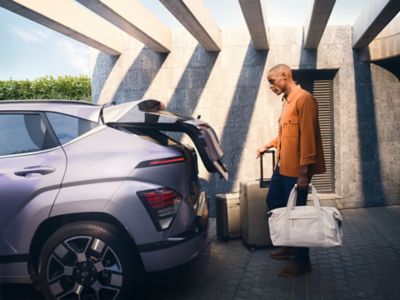 en mann bruker den smarte bagasjeromsåpneren på en KONA Electric. Foto