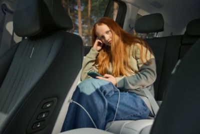 en ung jete lader telefonene i baksetet på IONIQ 9. Foto.