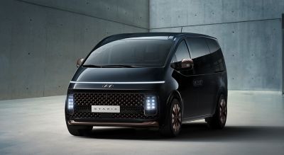 Ansicht von schräg vorne, ein Hyundai STARIA vor einer grauen Wand.