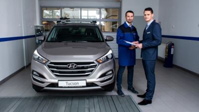 Mechanik i mężczyzna w garniturze obok samochodu Hyundai TUCSON