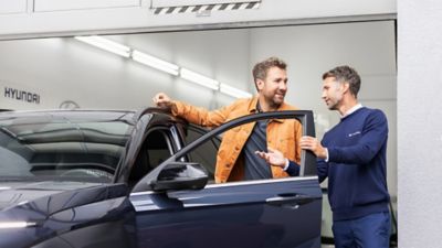 Dwóch mężczyzn rozmawiających obok samochodu Hyundai