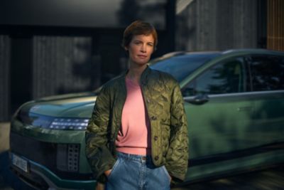 En dame står foran en parkert IONIQ 9. Foto.