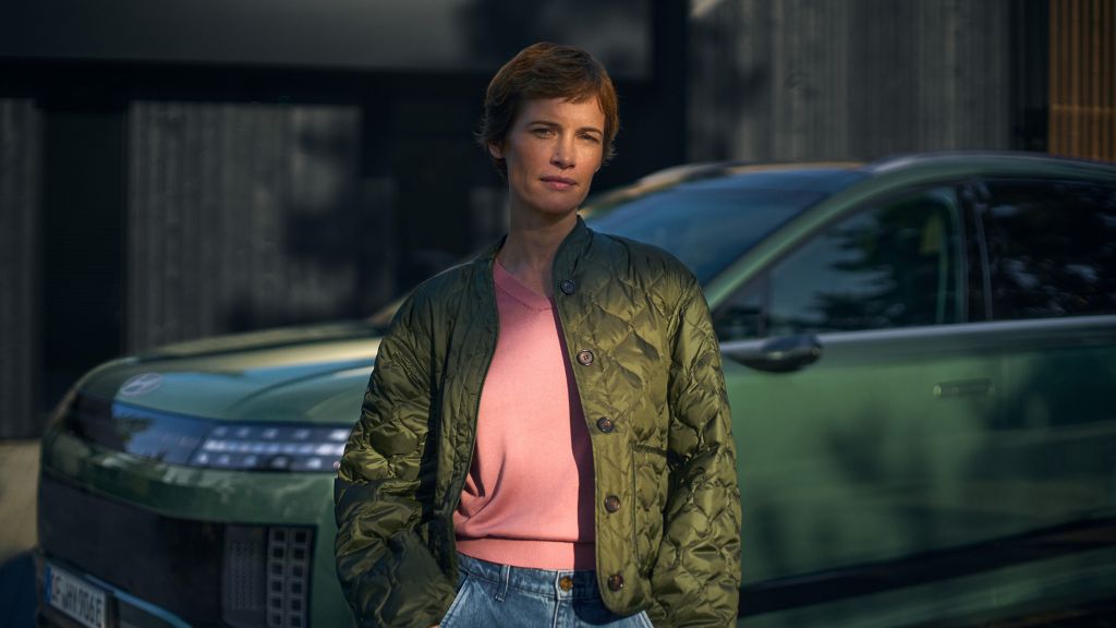 En dame står fpran en IONIQ 9. Foto.