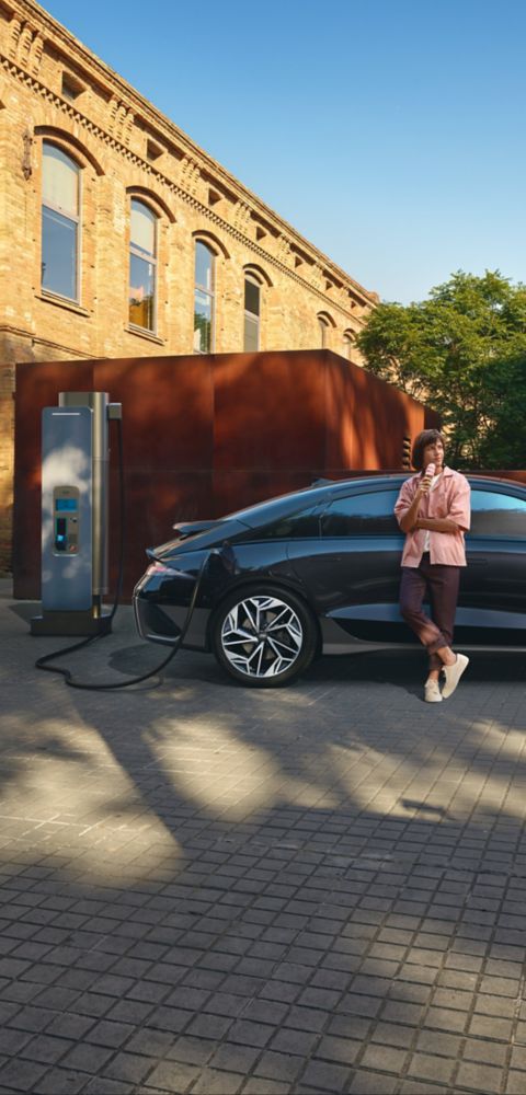 Hyundai i30 seen from rear three-quarter driving on a city street in front of modern buildings.