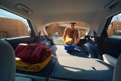 Blick aus einem Hyundai IONIQ 5 über die umgelegte Rückbank. Ein Mann belädt den Kofferraum.