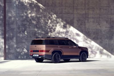 The Hyundai Santa Fe Hybrid parked in front of a high wall. 