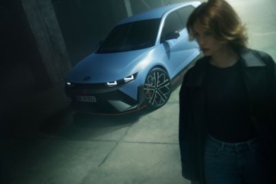 The all-new Hyundai KONA Electric in blue with a woman walking beside it.