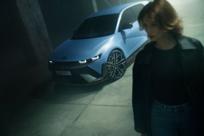 The Hyundai IONIQ 5 N Electric in performance blue with a woman walking beside it.