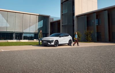 Hyundai KONA Electric ve slunečním světle s mužem, který odchází z garáže.