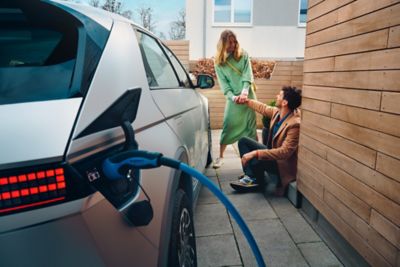 The Hyundai IONIQ 5 getting charged while a couple is laughing next to it.