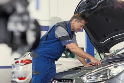 Hyundai technician working underneath the bonnet of a car