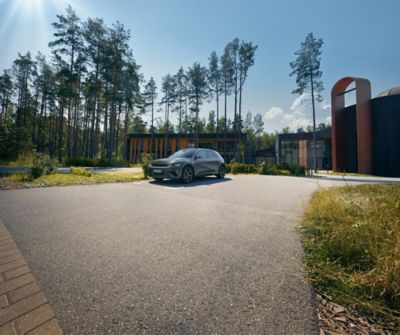 IONIQ 5 parkert ved et moderne bygg mens den lader. Foto.