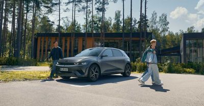 Blide mennesker går rundt en IONIQ 5. Foto.