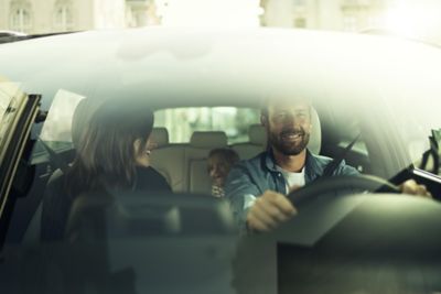 Looking inside a Hyundai through the windshield, a family in the car is looking happy.