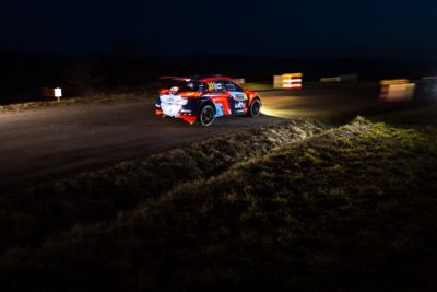Hyundai Motorsport customer racing rally car i20 R5 in action at night with headlights on.
