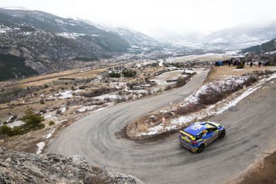 Hyundai Motorsport customer racing rally car i20 R5 in action driving a hairpin turn in the mountains.