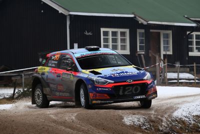 Hyundai Motorsport customer racing rally car i20 R5 in action on a snowy gravel road.