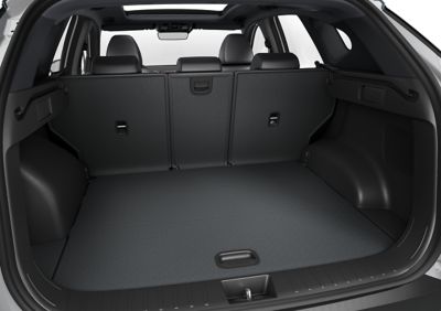 Otwarty bagażnik i złożone oparcia siedzeń nowego kompaktowego SUV-a Hyundai TUCSON Plug-in Hybrid.