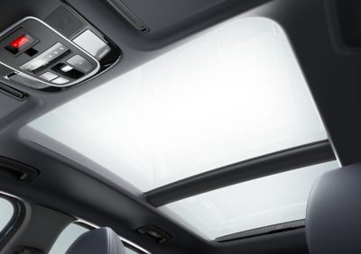 Der Dachhimmel eines Hyundai TUCSON Plug-in-Hybrid mit Bedienelementen und Panorama-Glas-Schiebedach. 