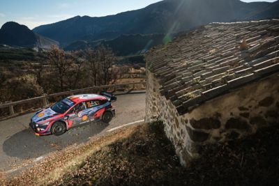 Samochód rajdowy Hyundai i30 N WRC na zakręcie na górskiej drodze.