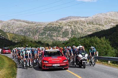 Lang rekke med syklister i et fantastisk landskap med Hyundai som følgebil i Arctic Race of Norway 2024. Foto.