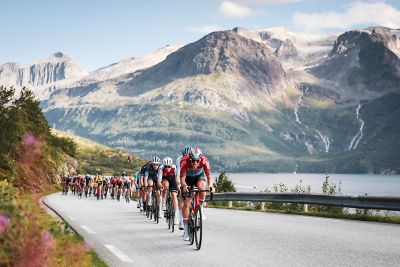 En lang rekke syklister i et fantastisk landskap i Arctic Race of Norway 2024. Foto.