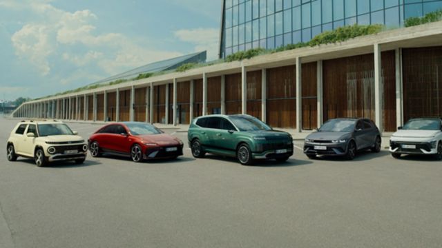Hyundai vehicle fleet displayed outside a modern office building with EV charging station.
