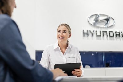 Hyundai fleet speaking to customer with tablet in hand.