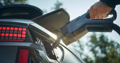 En som kobler en ladekabel til IONIQ 5. Foto.