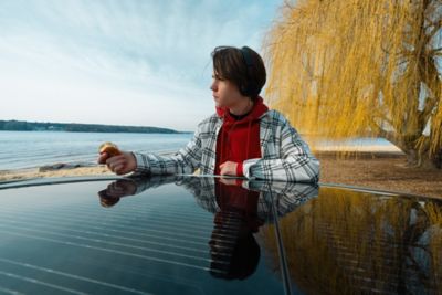 Un adolescent révise sur le toit à panneau solaire rechargeable du CUV 100% électrique Hyundai IONIQ.