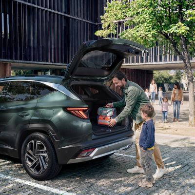 Hyundai TUCSON Plug-in Hybrid pripojený k nabíjačke pod stromami.