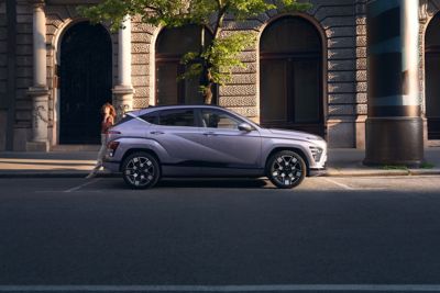 Vrouw leunt tegen de Hyundai KONA Electric in een stad.