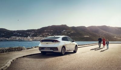 Nový Hyundai IONIQ Electric stojící na pobřeží ve městě.