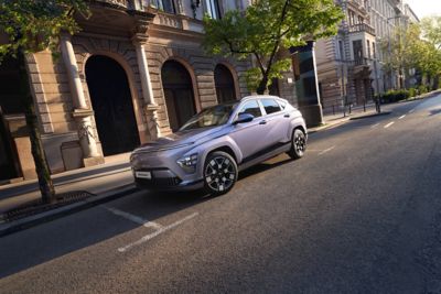Een Hyundai KONA Electric geparkeerd naast een gebouw in de stad.