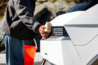 Nærbilde av en som vasker bilen med en svamp. foto.