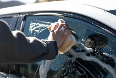 Nærbilde av en som vasker vinduet med en svamp. foto.