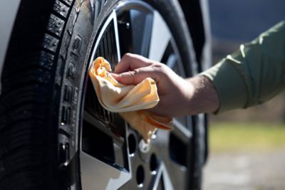 Nærbilde av en som tørker dekkene med en klut. foto.